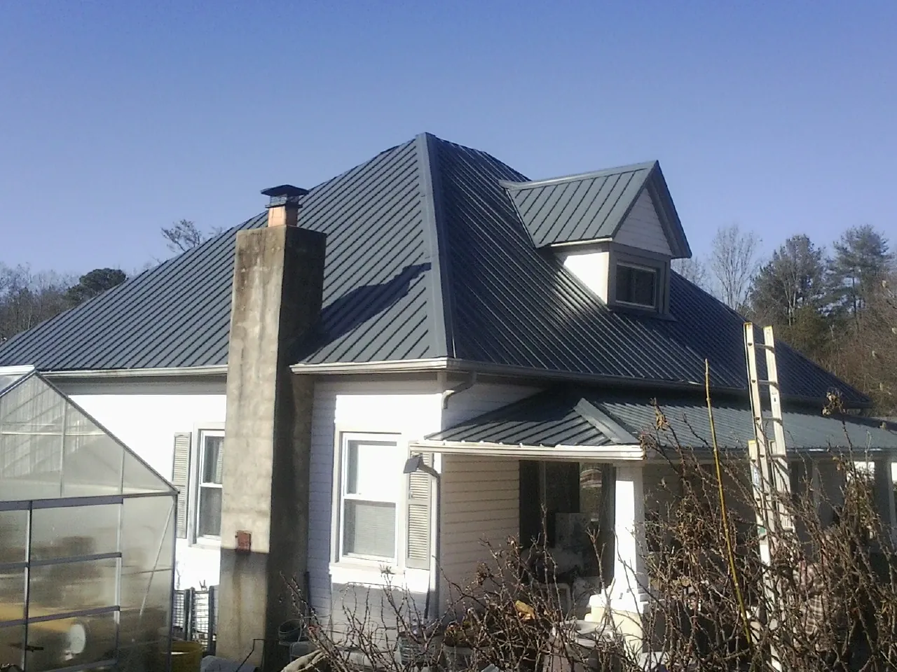 Dark blue standing seam metal roof on a white farmhouse with dormer — Slate & Tile Roof Repair by Roofing Brothers in Homeworth
