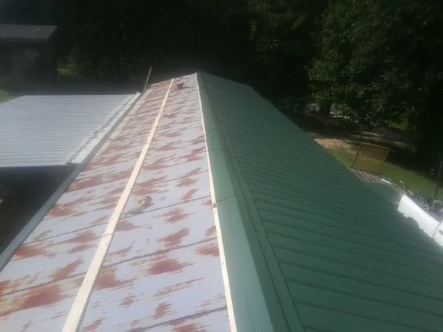Old rusted panels beside newly installed green metal roofing — Wind Damage Roof Repair by Roofing Brothers in Homeworth