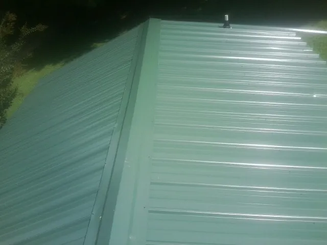 New green metal panels meeting at the ridge of a roof — Flat Roof Repair work by our crew in Homeworth