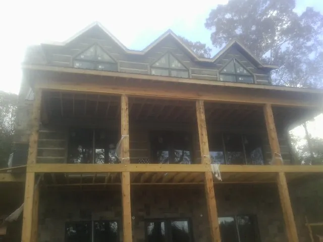 Dormers and porch framing on a large log home under construction — Roof Coating work by our crew in Homeworth
