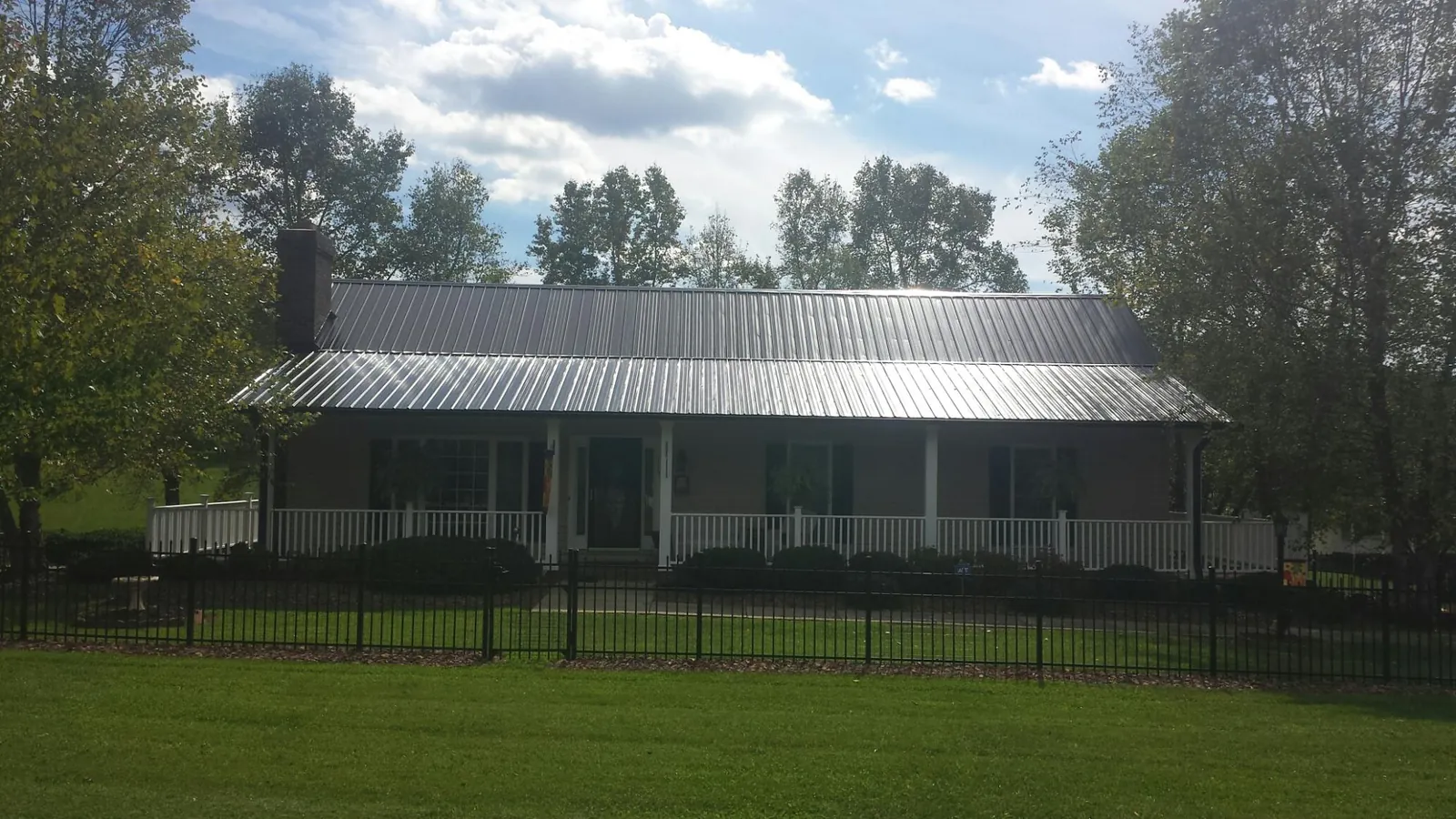 Gray metal roof on a brick ranch with a full width front porch — Gutter Guard Installation work by our crew in Homeworth