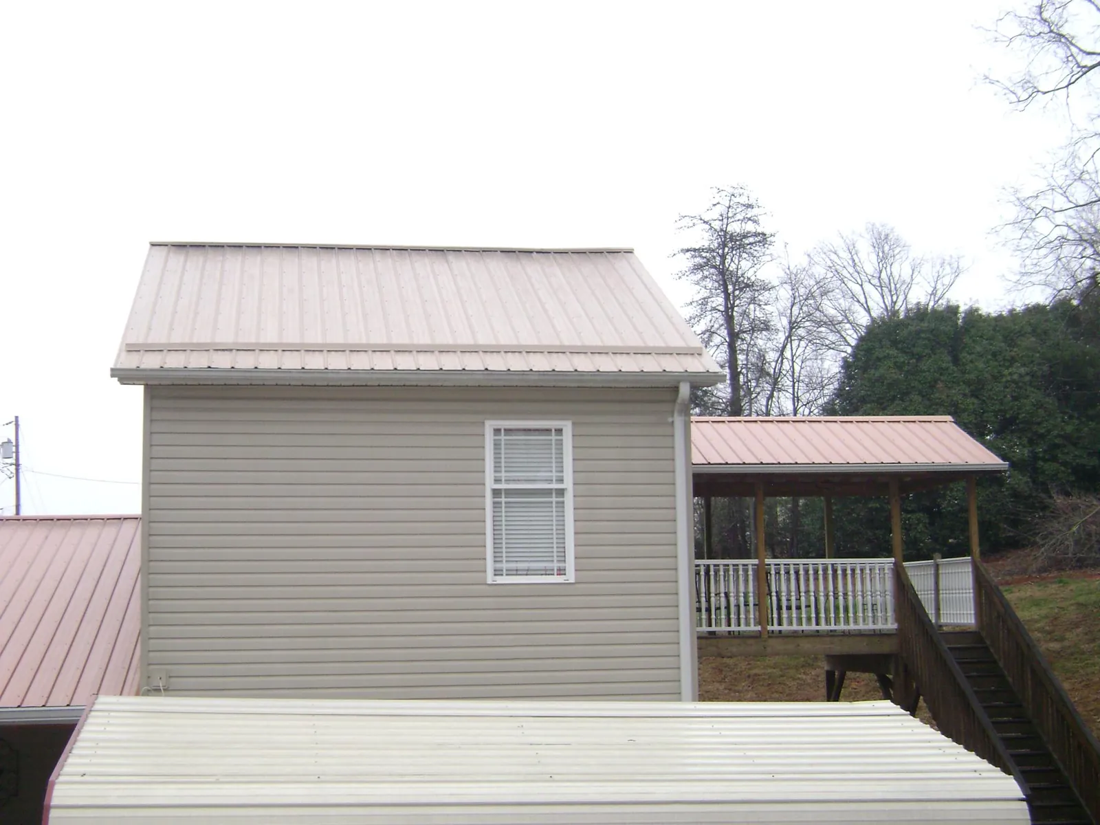 Tan metal roofs on a two story addition and attached porch, from a Roof Replacement job in Homeworth