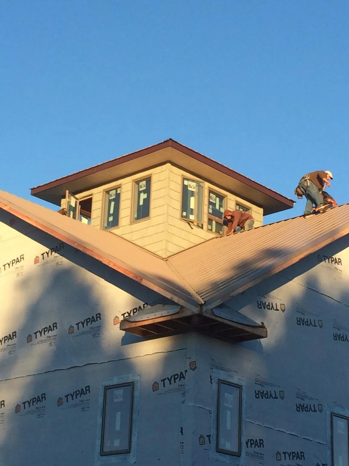 Roofers working around a rooftop cupola on a new metal roof at sunset — Roof Waterproofing in Homeworth by Roofing Brothers